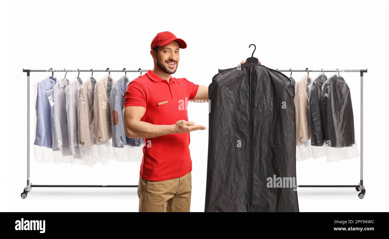 Laundry worker holding clothes on a hanger with a case cover  in front of clothing racks isolated on a white background Stock Photo