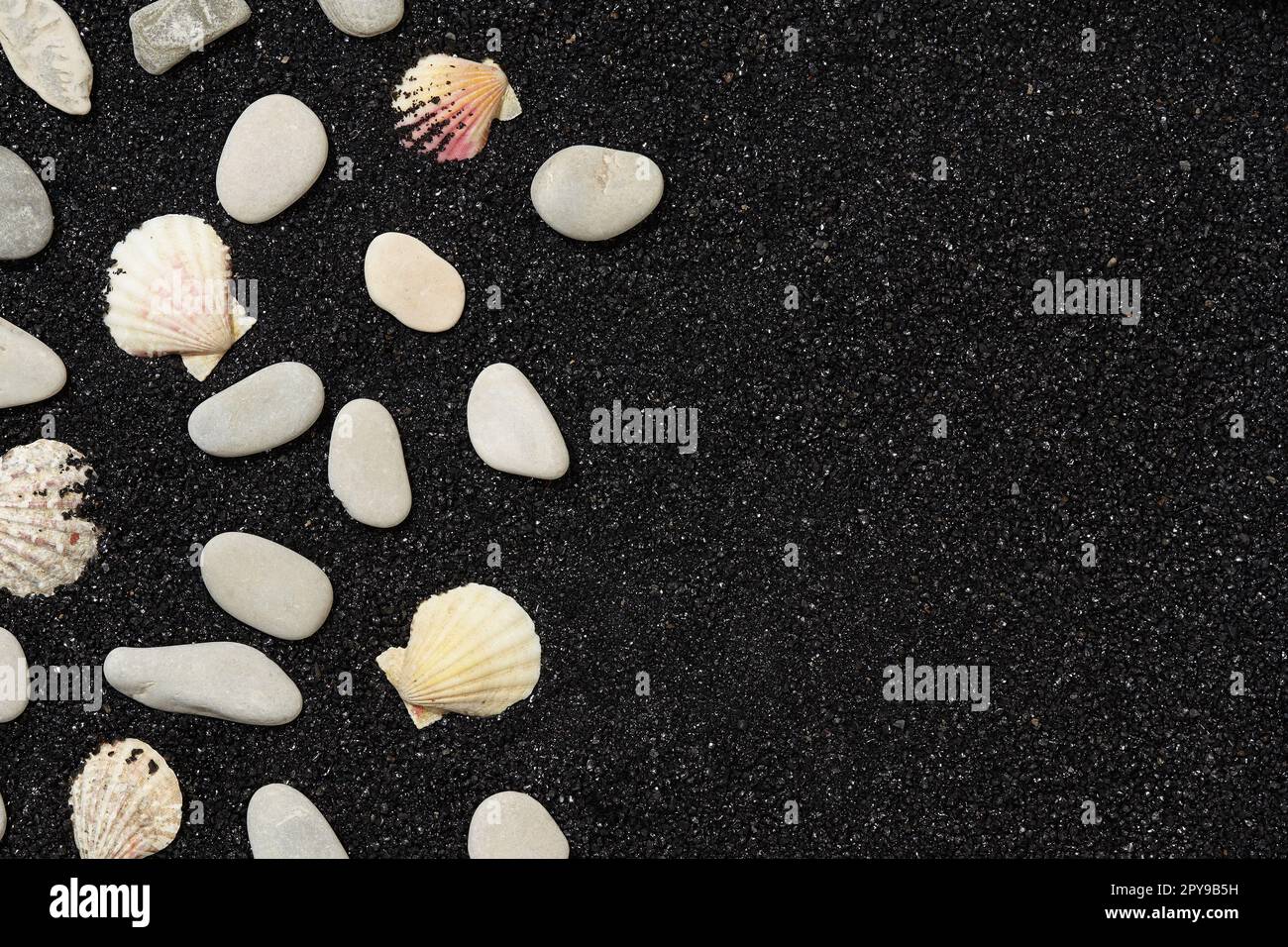 Black sand with sea shells and pebbles. Travel and vacations concept background Stock Photo