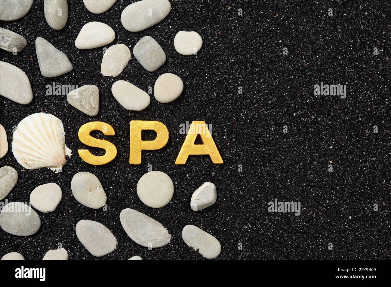 Spa word in black sand with pebbles. Background with space for your own text Stock Photo