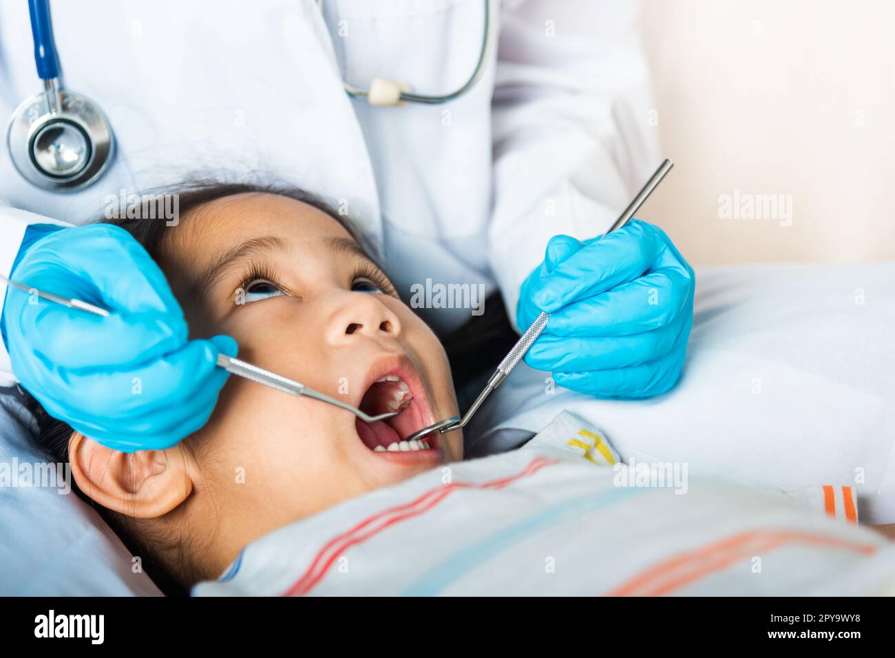 Doctor examines oral cavity of little child uses mouth mirror to