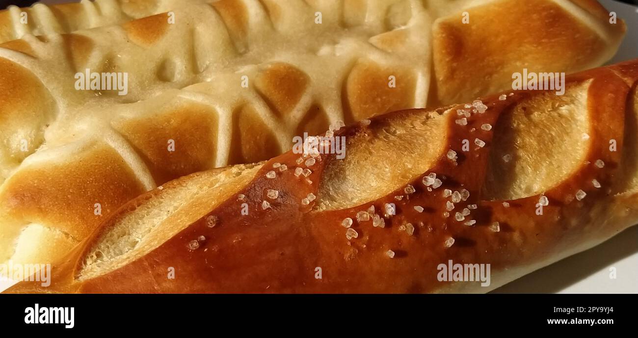 Delicious appetizing freshly baked fatty wheat buns sprinkled with salt and salted gravy. Close-up. White bread containing gluten, many calories and carbohydrates. Quick everyday breakfast. Diabetes Stock Photo