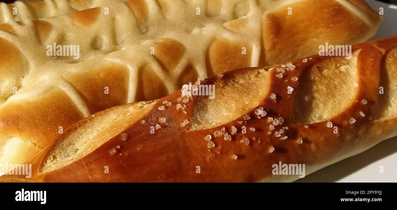 Delicious appetizing freshly baked fatty wheat buns sprinkled with salt and salted gravy. Close-up. White bread containing gluten, many calories and carbohydrates. Quick everyday breakfast. Diabetes Stock Photo