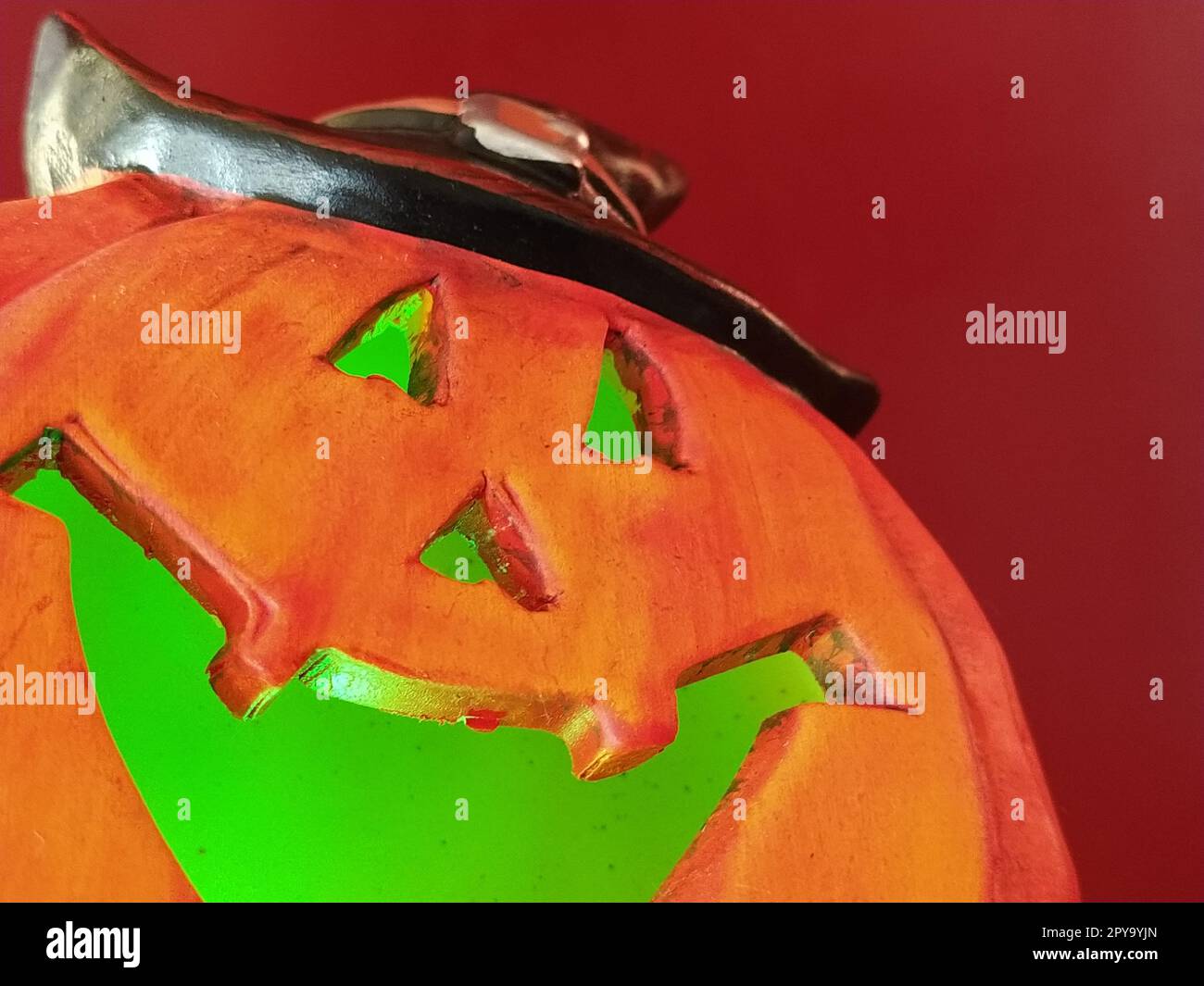 Bright orange Halloween pumpkin. Cut holes for mouth, nose and eyes. Green scary glow from the inside of the pumpkin. Close-up. The sinister laugh of the monster. Blurring Stock Photo