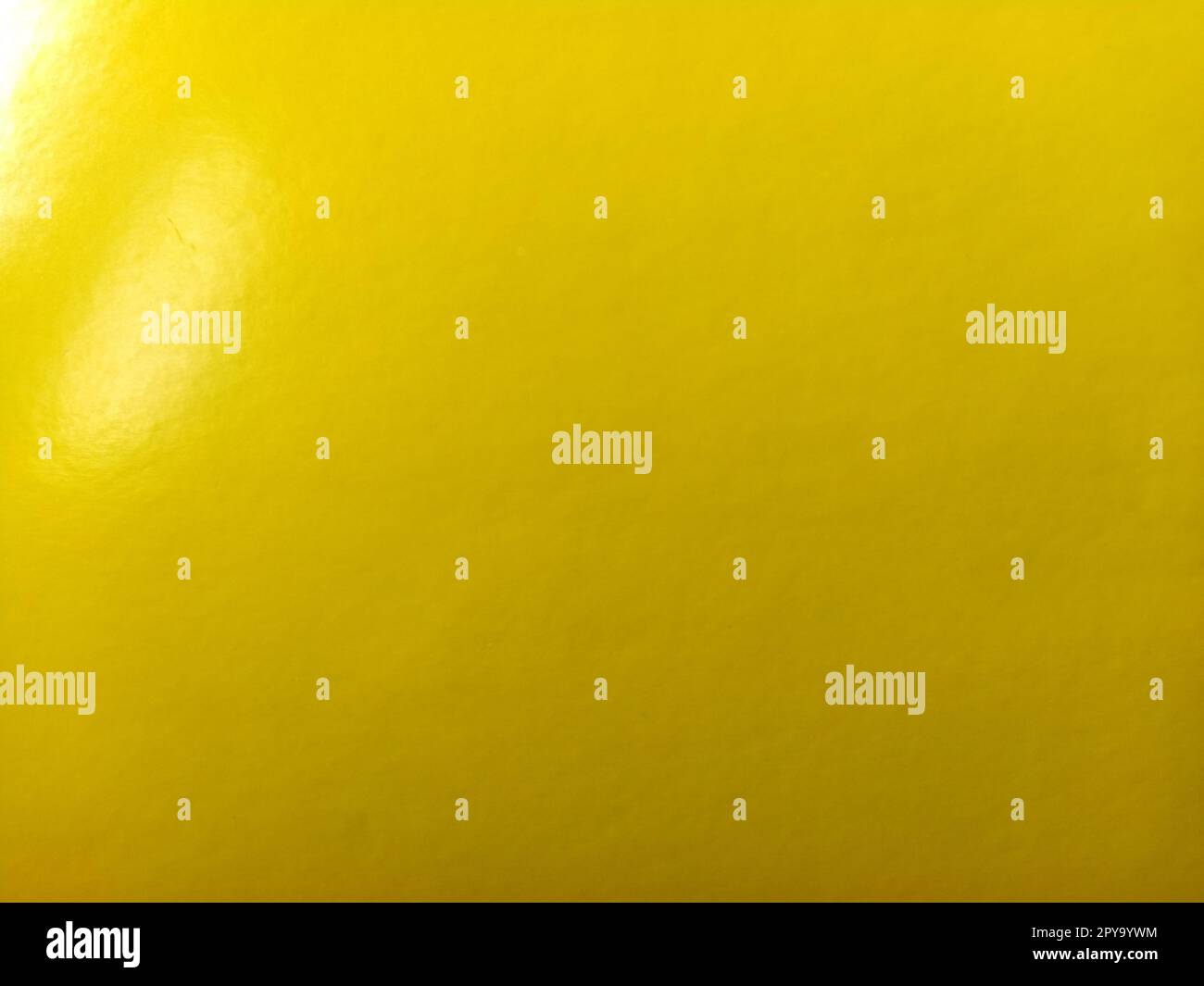 Beautiful bright yellow background. Close-up sheet of shiny reflective incident light paper. Pure fun color. Intense shade of yellow, close to gold or sunny with high reflectivity. Stock Photo