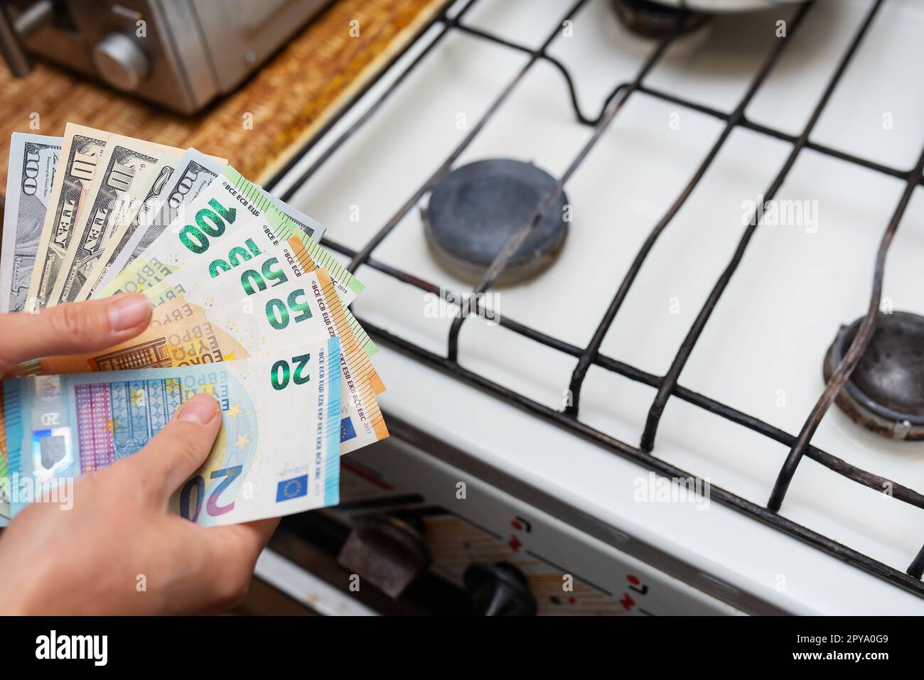 Payment of utility bills, calculations on a calculator. Euro and dollar bills lie near a burning gas burner. The concept of increasing the cost of natural gas supply and payment. Energy crisis, top view. Stock Photo