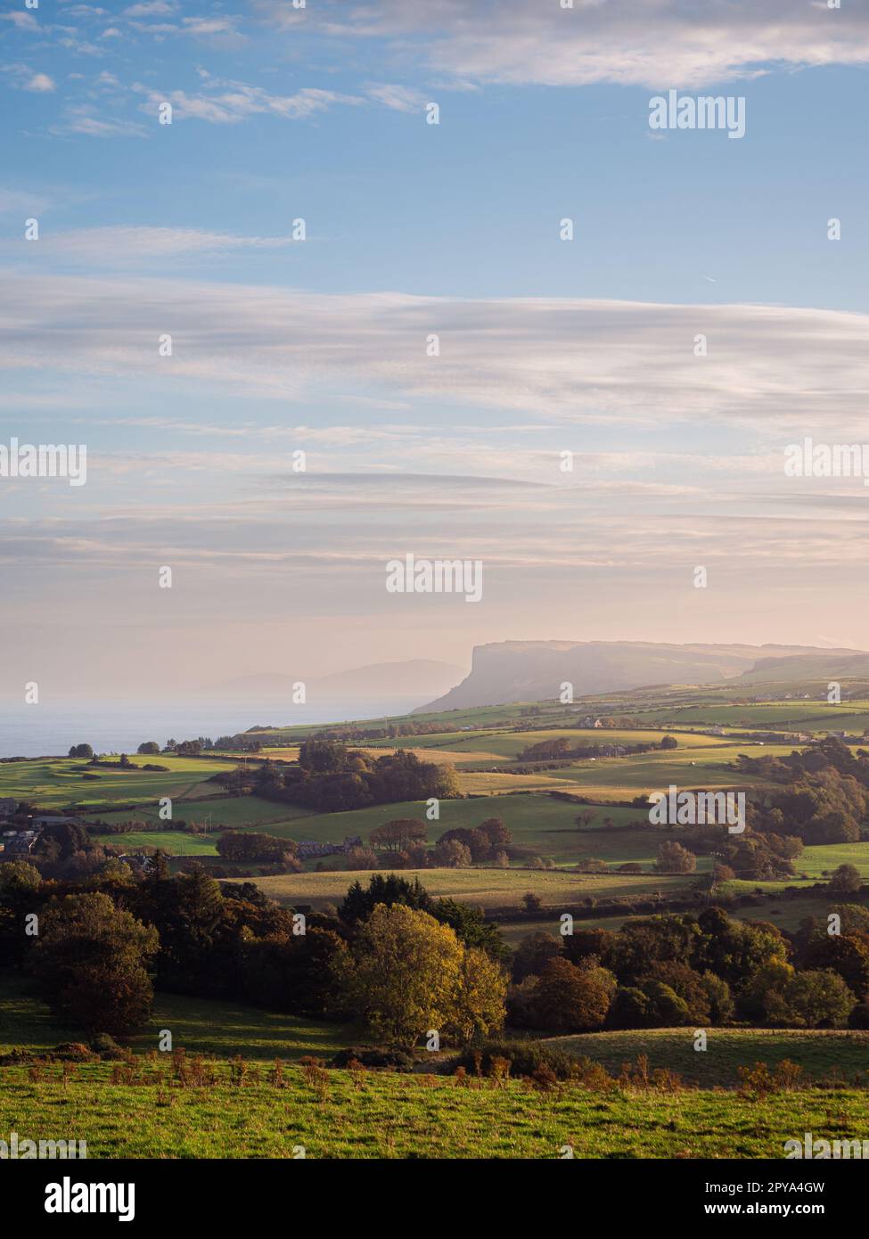 A view of the rural countryside in Northern Ireland in the town of Ballycastle. Fields in the foreground lead to the ocean in the background. Stock Photo