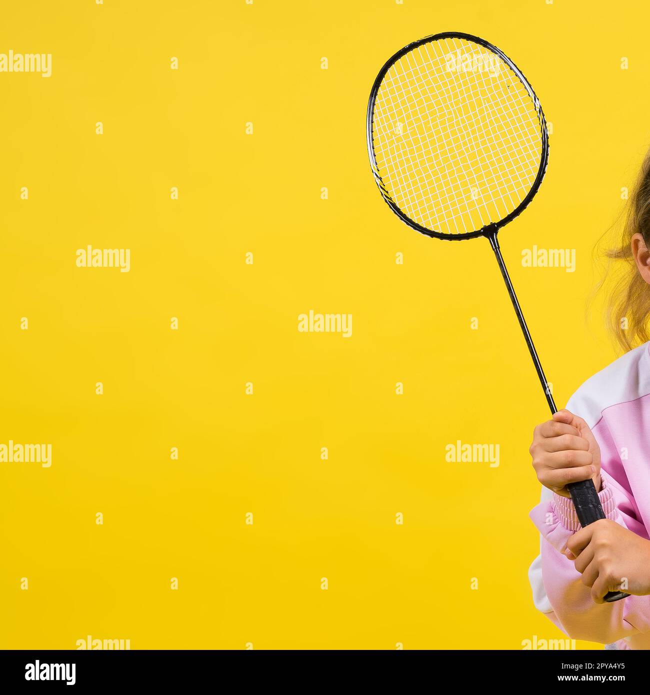 Full length studio photo of ten year old girl holding badminton racket and isolated on yellow