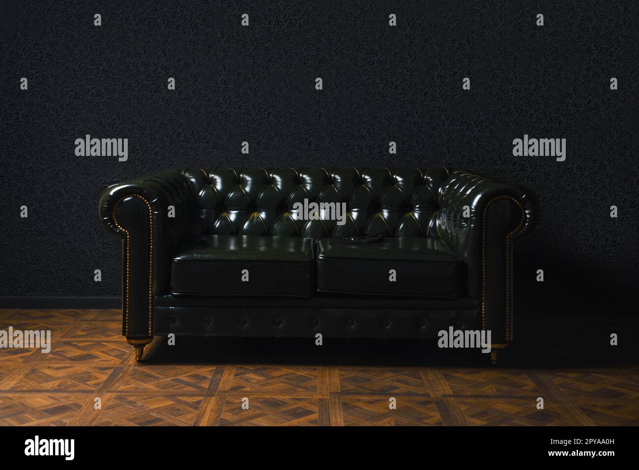 Glossy leather couch next to black wall Stock Photo
