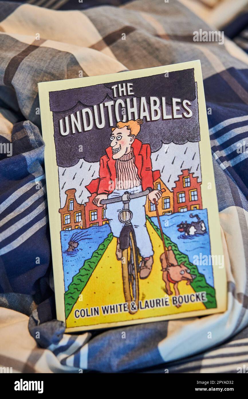 A light blue blanket laid across a bed, with a closed book resting on