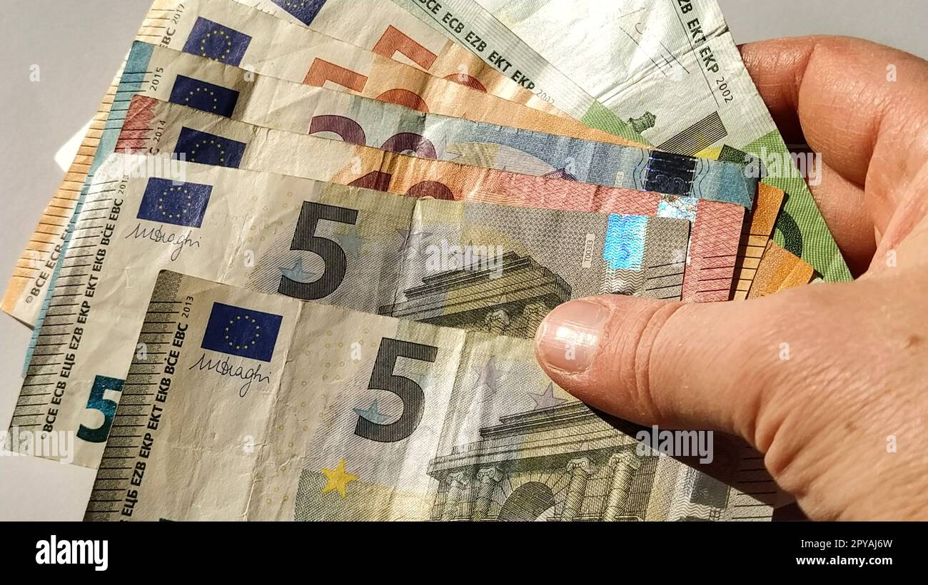 Euro paper notes. European currency on a white background close-up. Hand and fingers of an elderly person or middle-aged woman on money. Bank notes of the Central Bank for 5, 10, 20, 50 and 100 Stock Photo