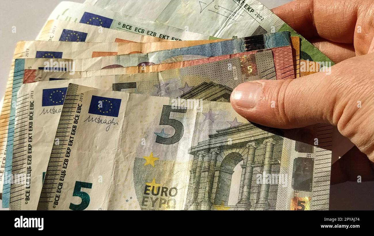Euro paper notes. European currency on a white background close-up. Hand and fingers of an elderly person or middle-aged woman on money. Bank notes of the Central Bank for 5, 10, 20, 50 and 100 Stock Photo