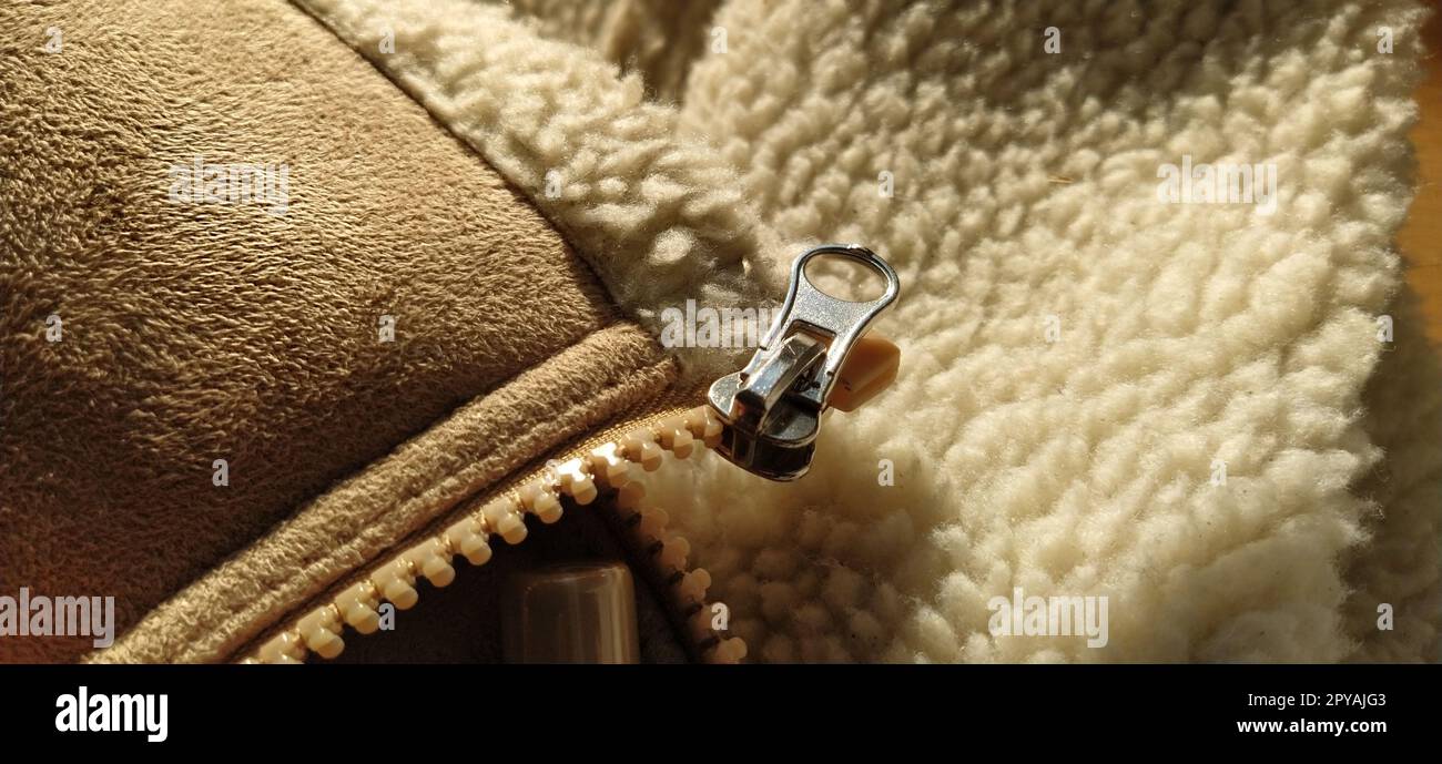 texture of leather and zipper. Zipper on suede sheepskin clothing. The metal element is the clasp. The fur on the hem of a leather product. Close-up sewing supplies. Work of the cutter and seamstress Stock Photo