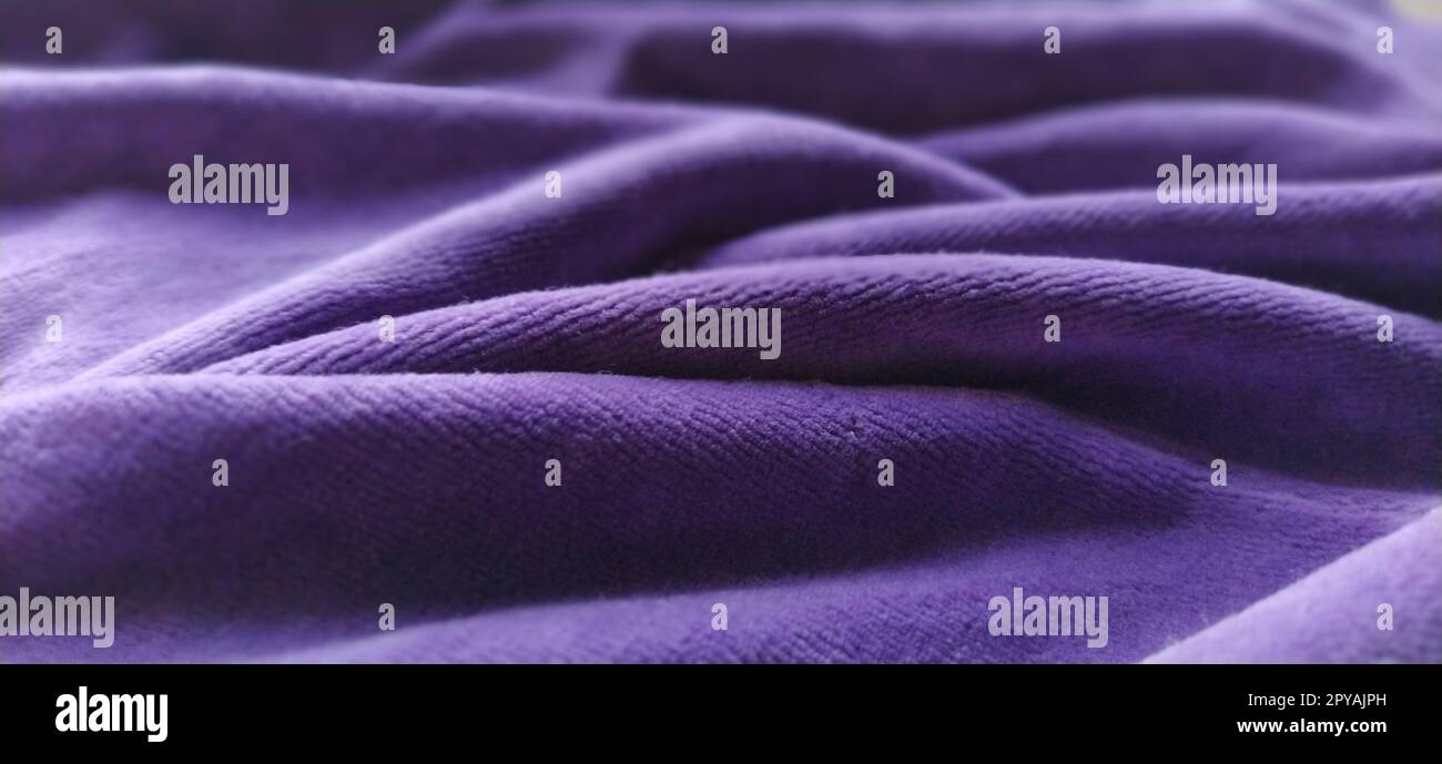 Fabric sheer curtain fabric. Beautiful violet color. Soft velvet with a pile. The curtain material is carelessly folded and wrinkled on a horizontal surface. Fabric sample. Interior design option. Stock Photo
