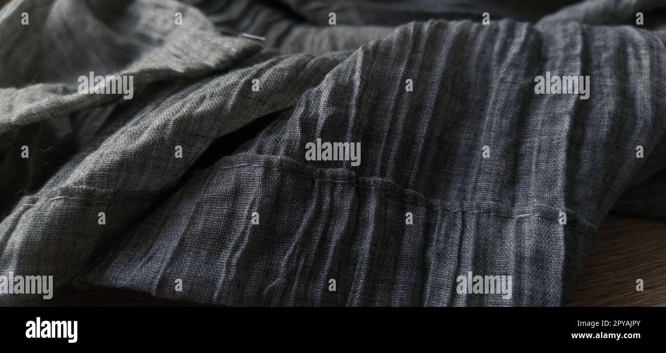 Gray pleated fabric or crumpled textile closeup. Light translucent curtains or tulle in the Scandinavian style. The lower edge of the curtain is hemmed 2-3 cm from the edge. Soft focus. Stock Photo