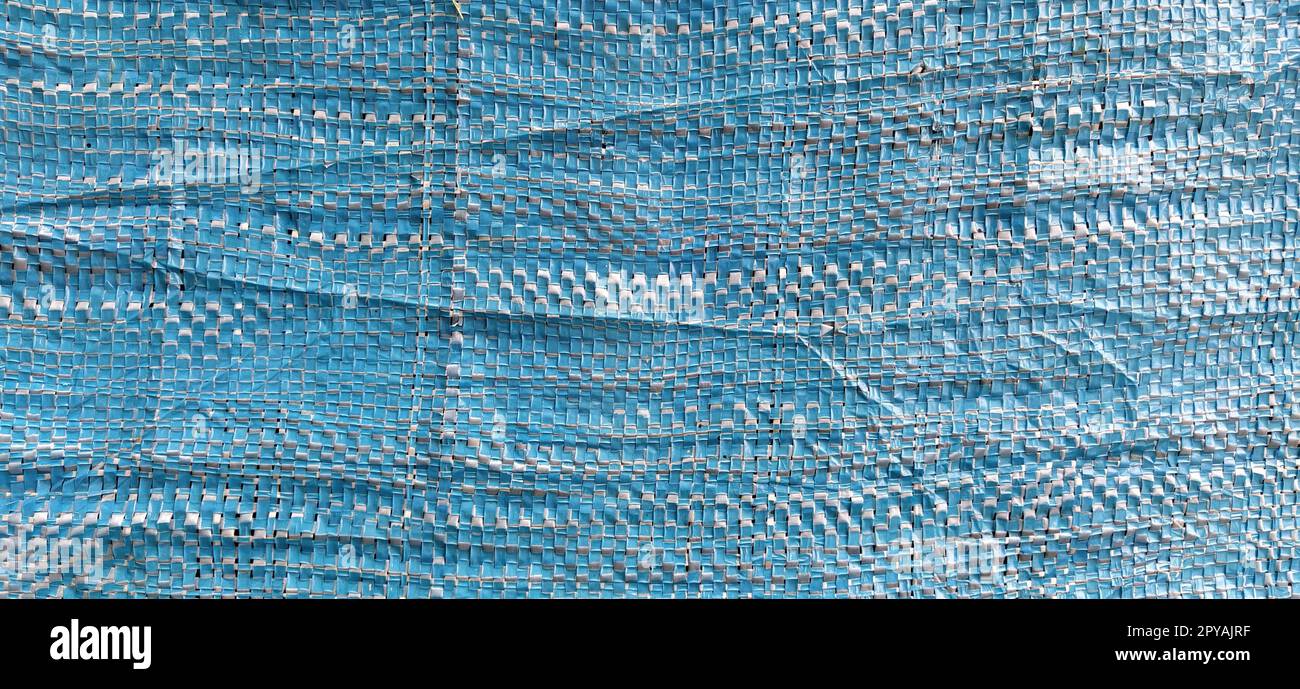 Blue synthetic burlap, close-up. Polyethylene material. Interlacing of polyethylene fibers and threads. Folds and bruises. Packing and packaging material Stock Photo