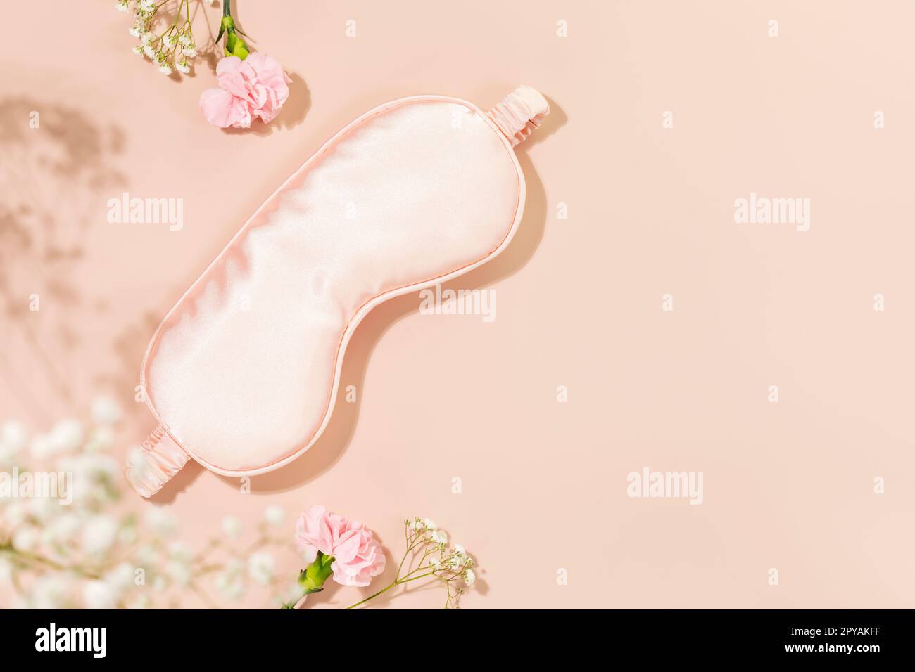 Pink mask for sleep and tender spring flowers on pink background. Insomnia or depression treatment for sleepless nights. Concept of healthy sleep, sel Stock Photo