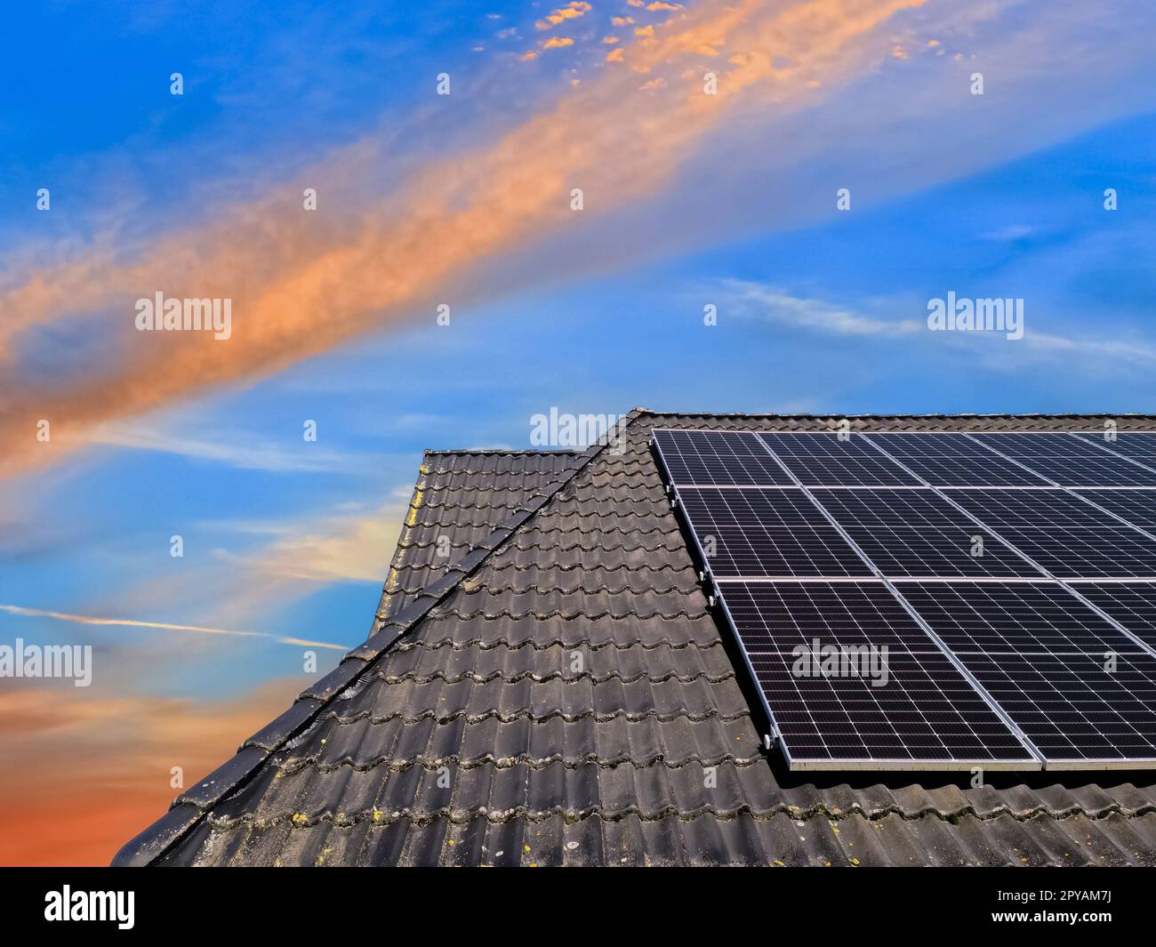 Colorful sunset on solar panels producing clean energy on a roof of a ...