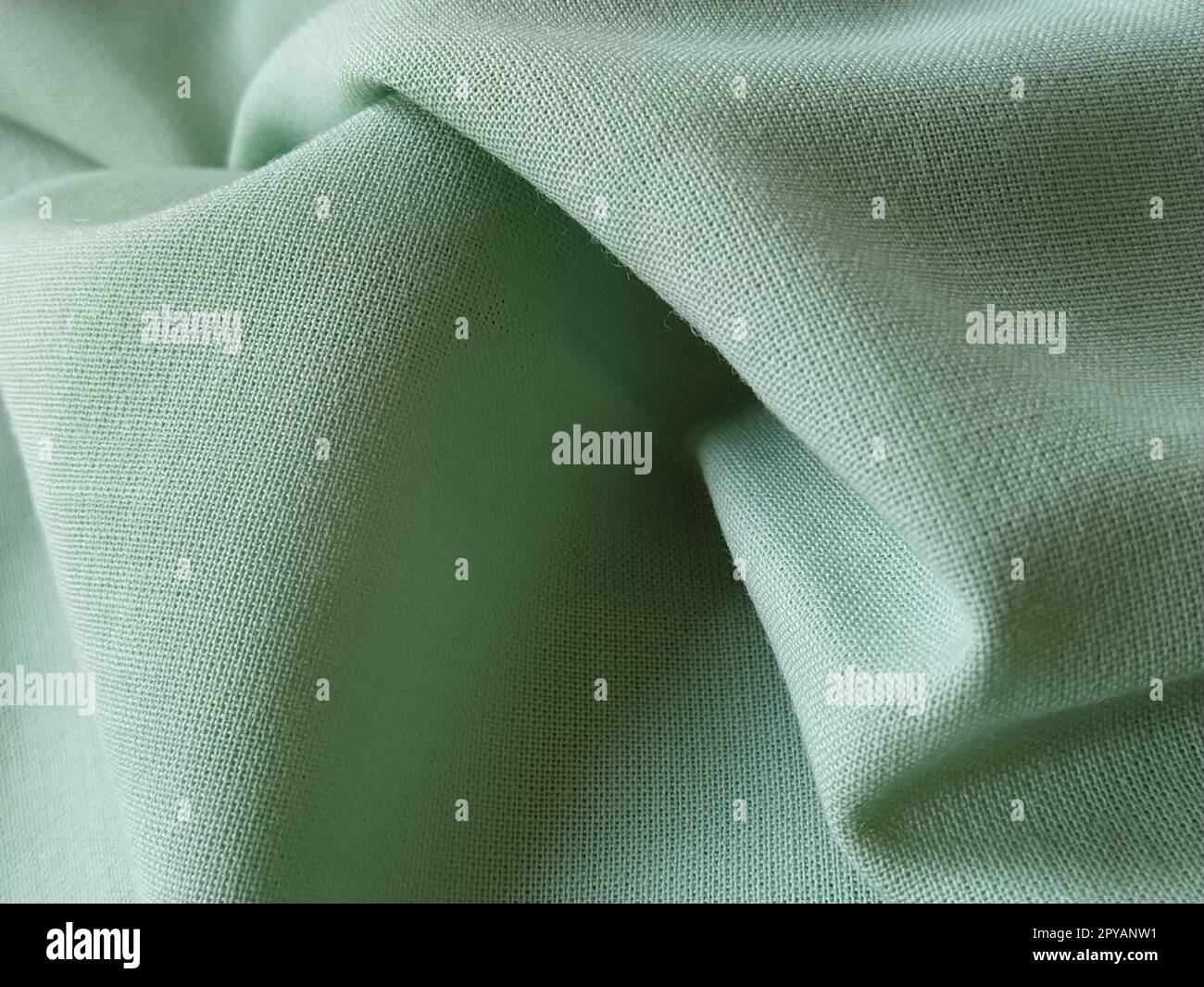 Close up of a woolen fabric of green color. Abstract canvas background, empty template. Thin natural fabric, wool or linen Stock Photo