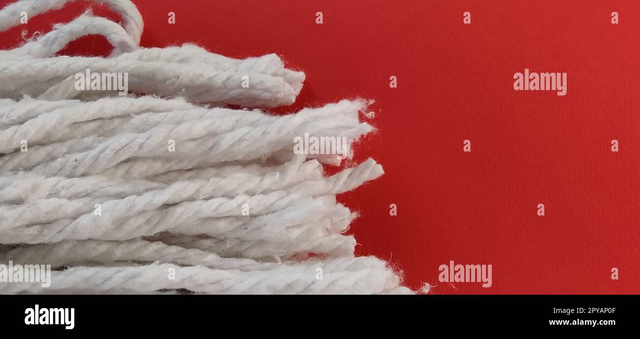 Cotton Rope Wringer Mop Attachment. The material is wrung out with a single rotary motion, avoids getting hands dirty and shortens the cleaning time. The cotton nozzle absorbs water. Red background Stock Photo