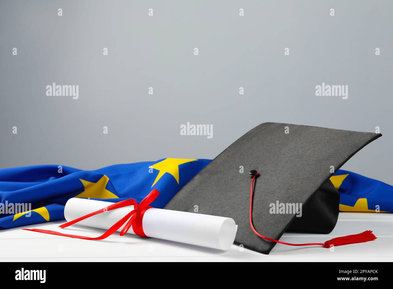 Black graduation cap, diploma and flag of European Union on white ...