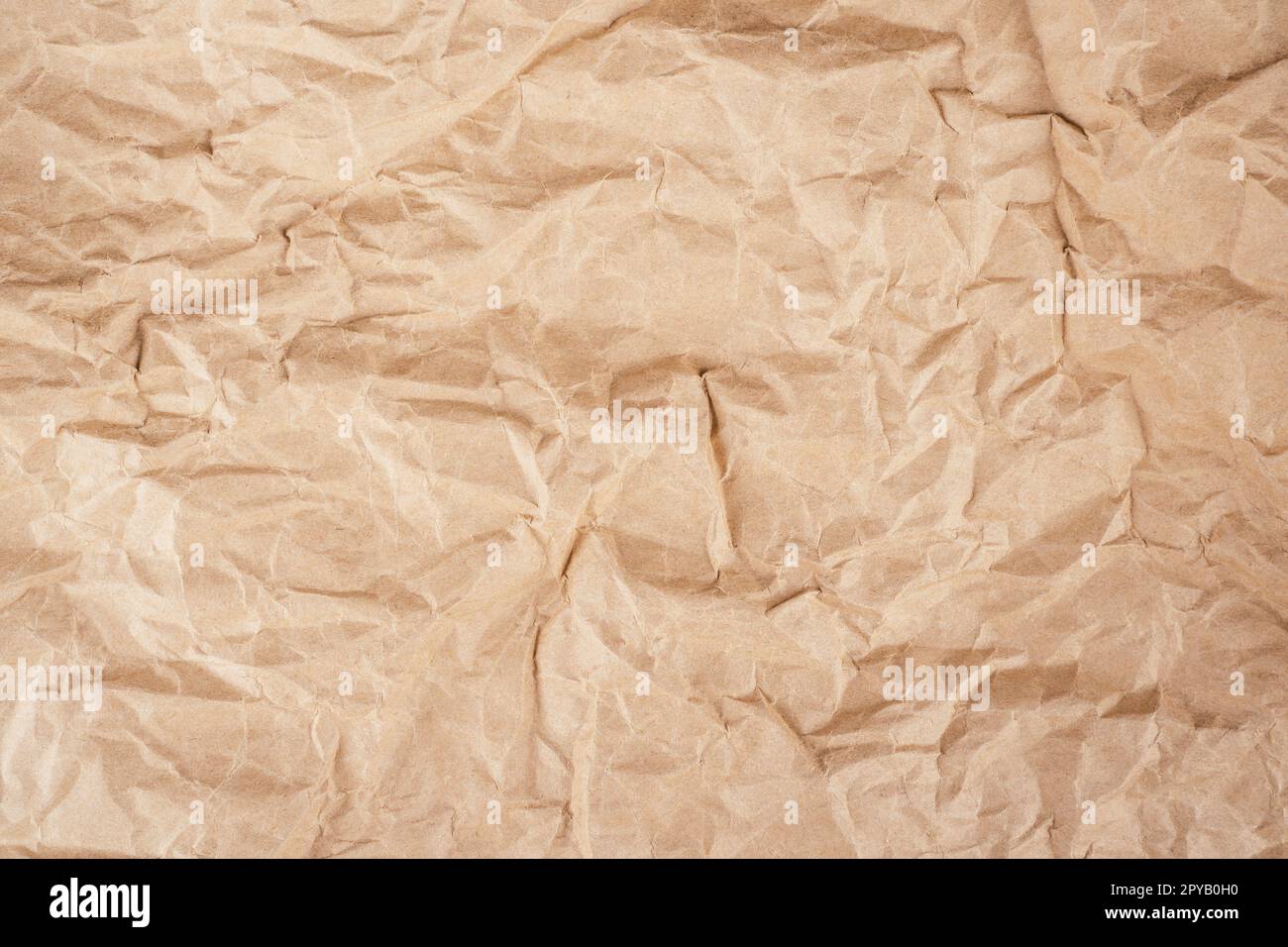 Background image of rough crumpled recycled textured kraft paper. Top view, copy space Stock Photo