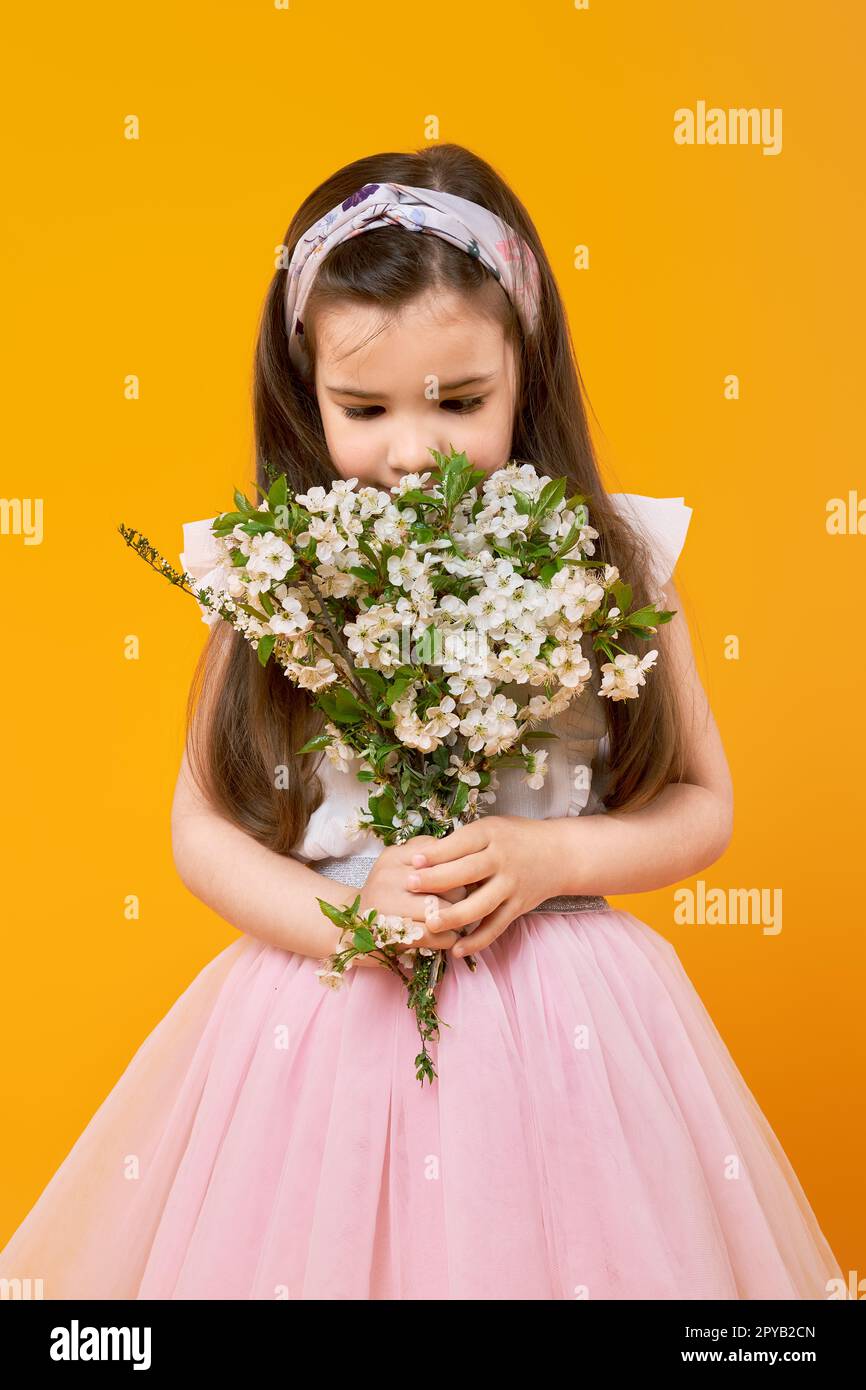 Cute little girl sniffing the bouquet of spring flowers Stock Photo