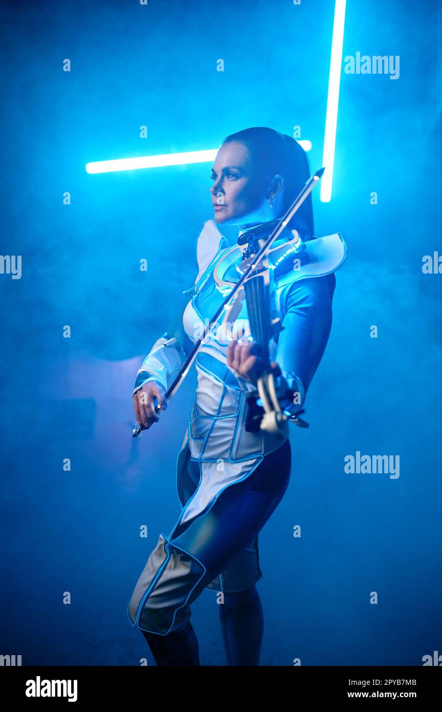 Beautiful violinist girl playing electric violin on stage with neon