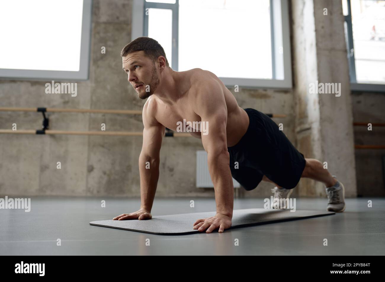 Young athletic man doing push-ups physical workout in gym Stock Photo