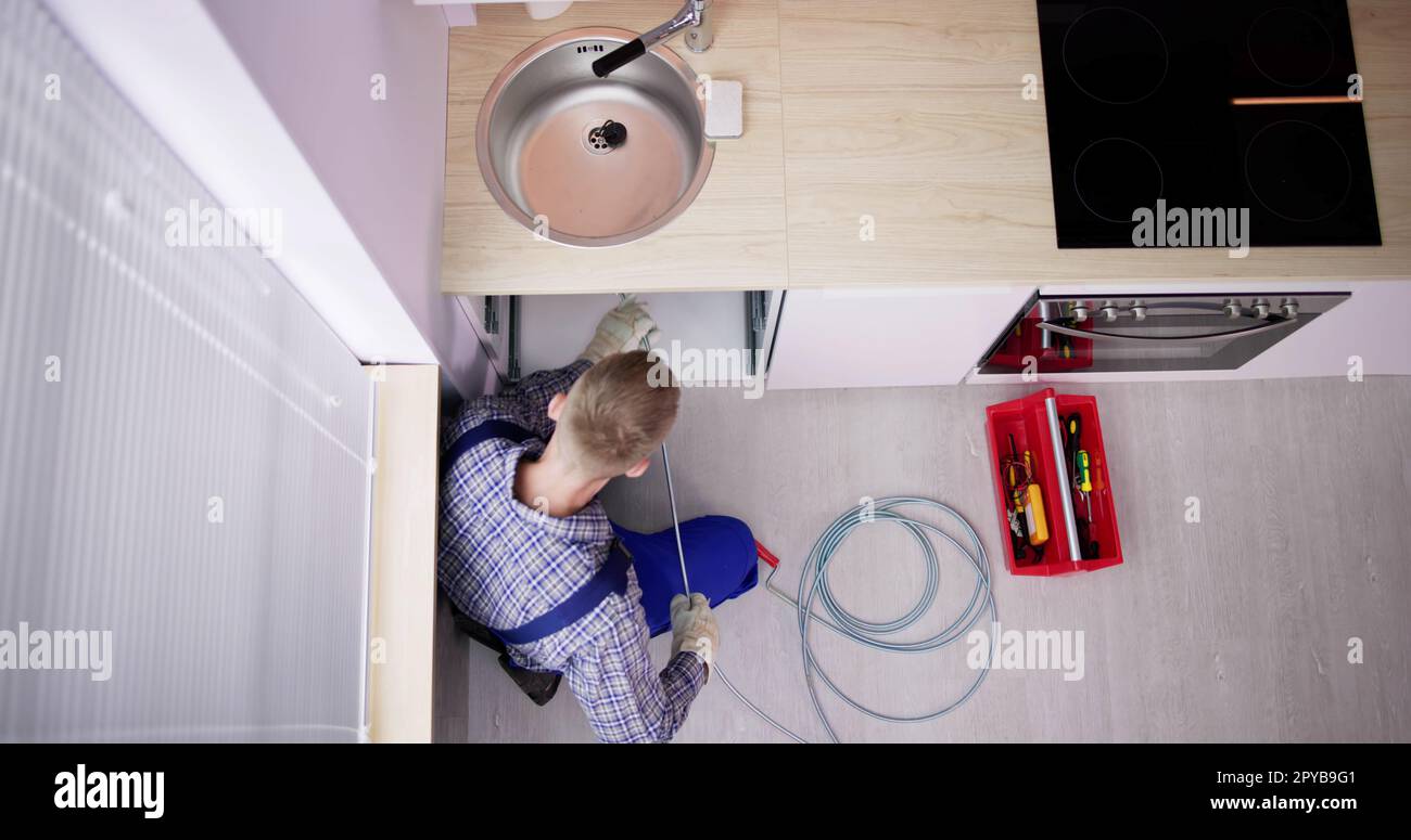 Plumber Drain Cleaning Services In Kitchen Stock Photo
