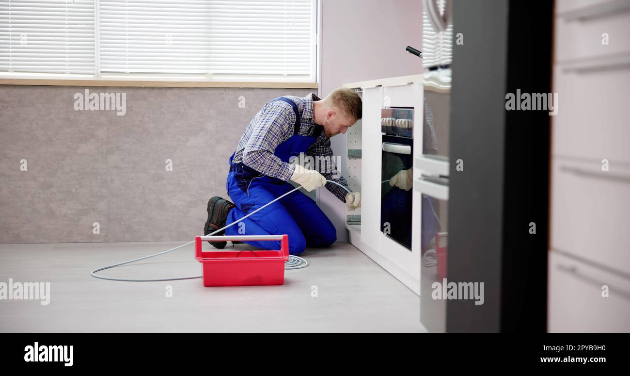 Plumber Drain Cleaning Services In Kitchen Stock Photo