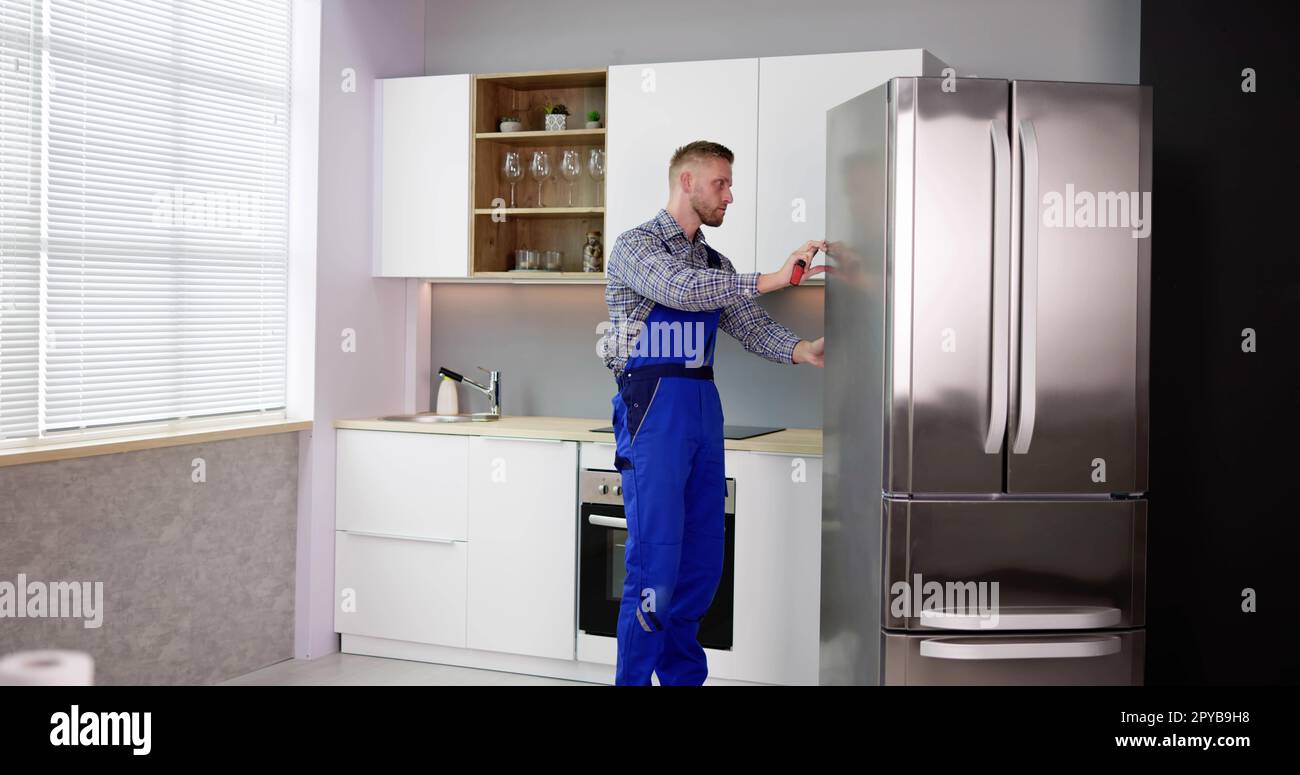 Male Worker Repairing Refrigerator With Screwdriver Stock Photo