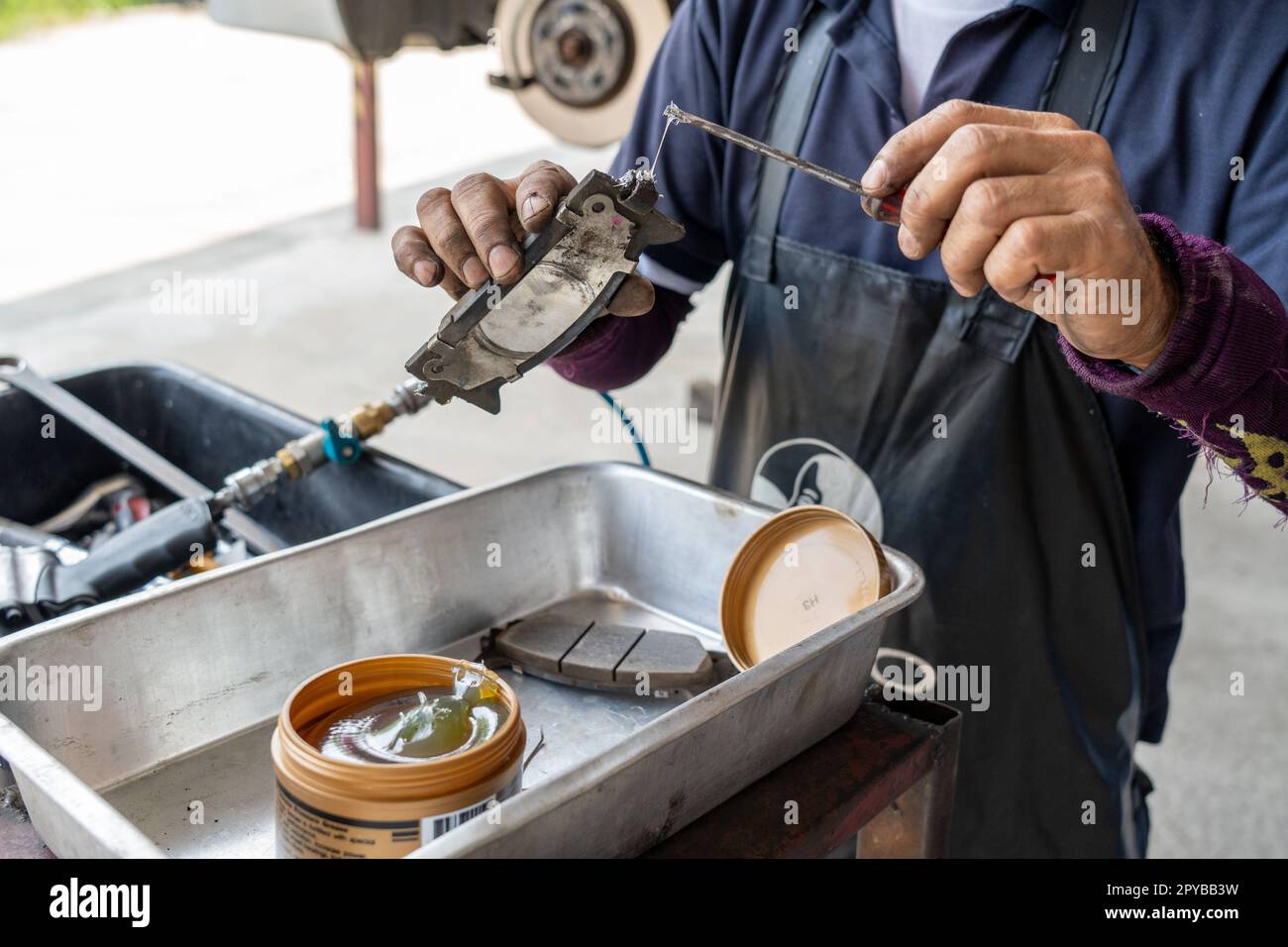 Auto mechanic putting lubricating grease oil on the break shoe before
