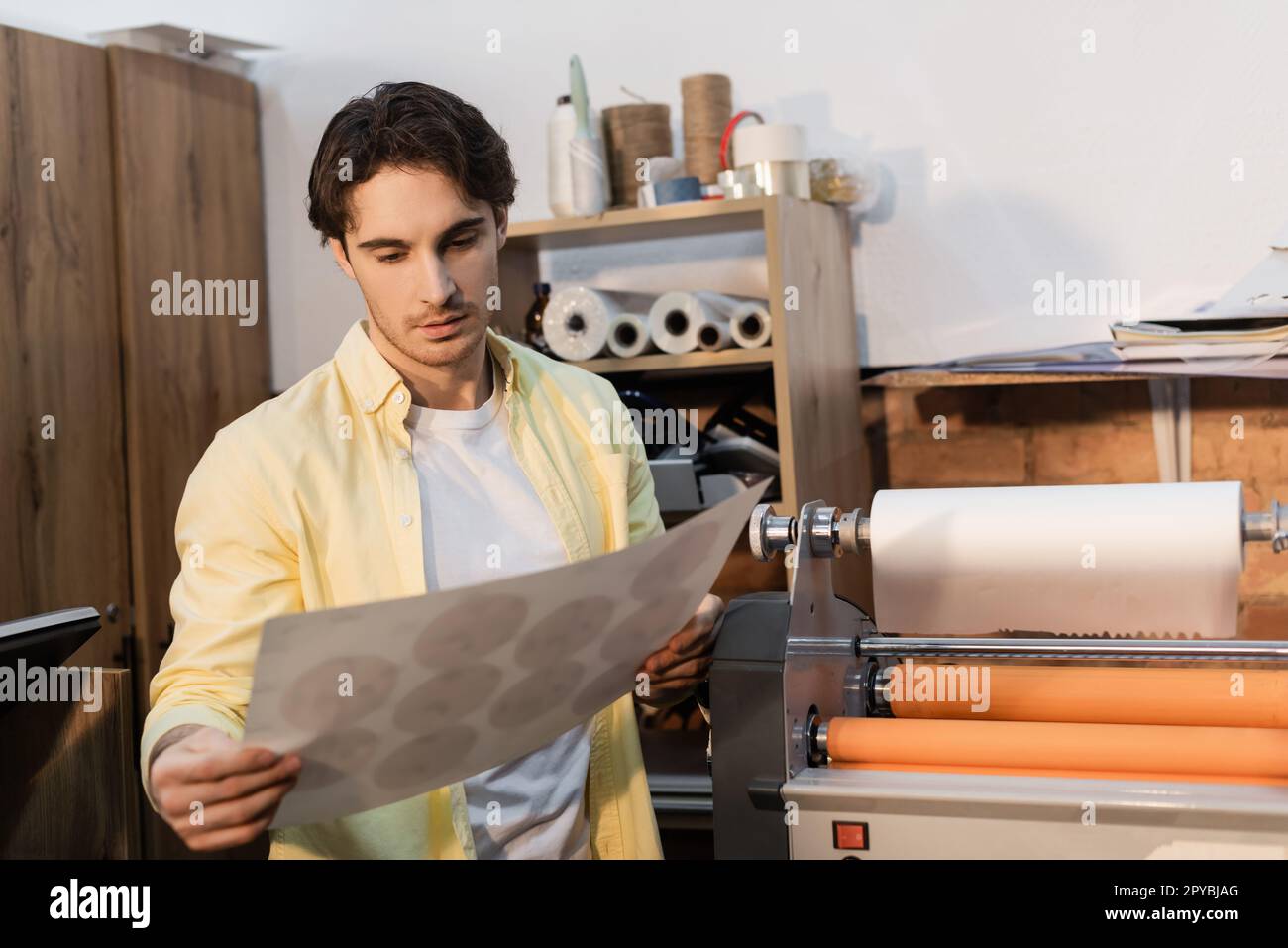 typographer looking at printed paper near professional print plotter,stock image Stock Photo