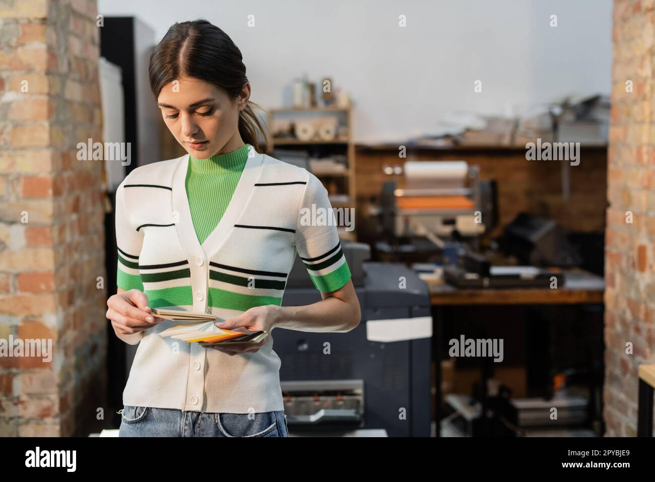 pretty typographer choosing color while holding samples in modern print center,stock image Stock Photo