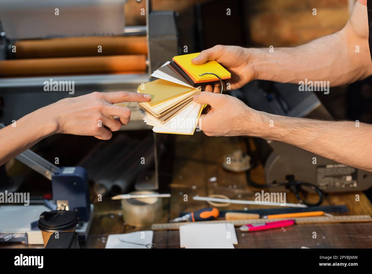partial view of typographer pointing at color samples in print center ...