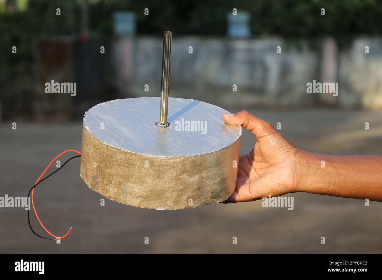 Big dc motor with shaft held in the hand. Single shaft motor powered by