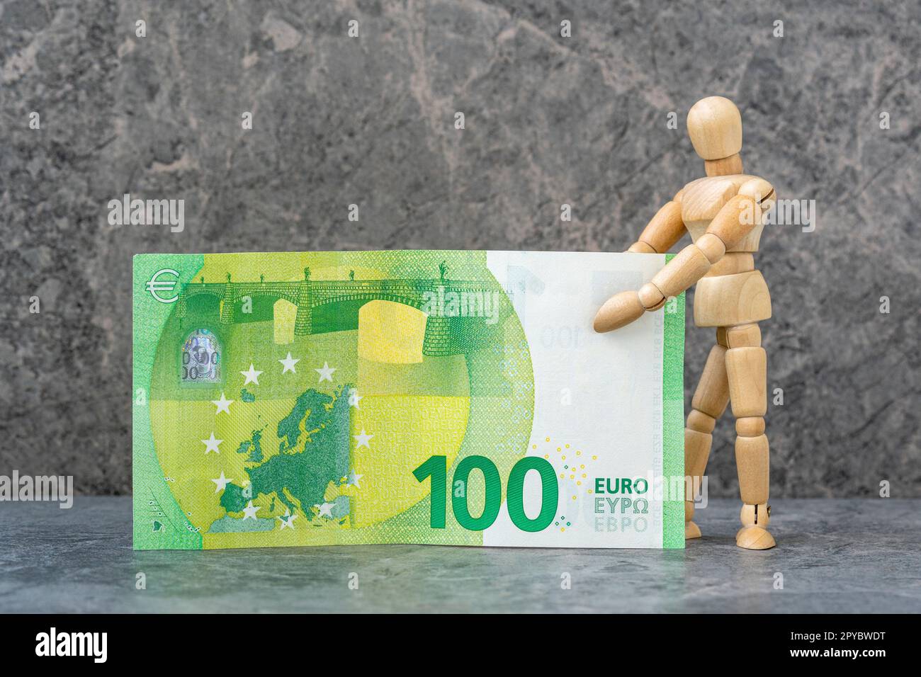 Wooden mannequin holding one hundred Euro banknote Stock Photo