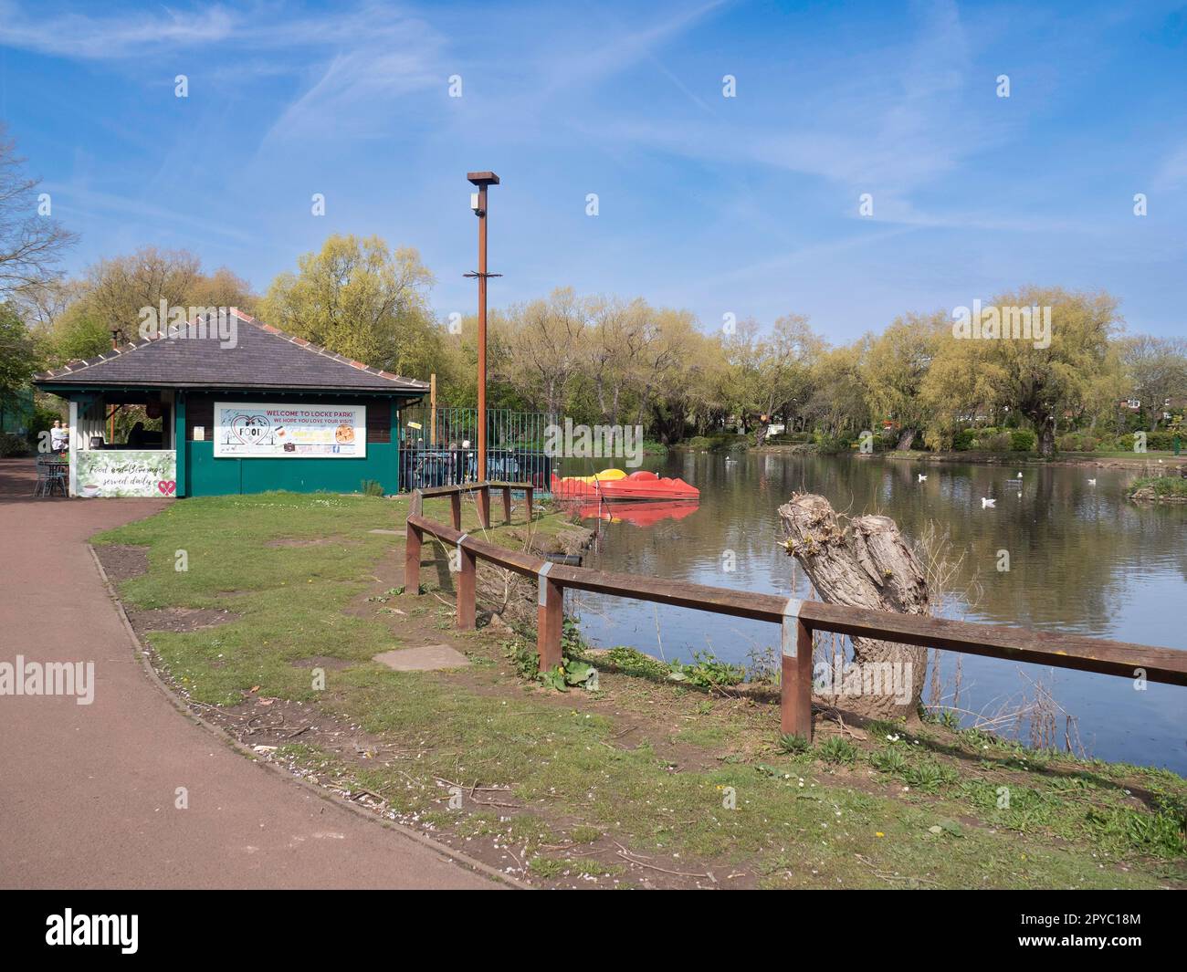 Locke Park Lake Redcar on a sunny spring day showing the café and red and yellow pedalo boats for hire Stock Photo
