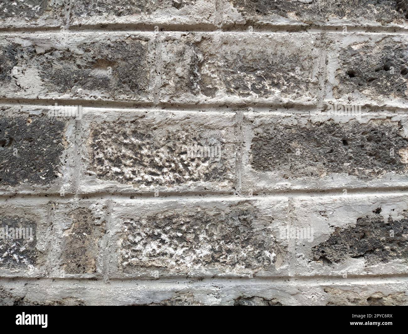Weathered aged stone masonry of old house. Ancient brick wall background. Old uneven scratched stone bricks texture. Turkish building wall. Rough limestone wall backdrop Stock Photo