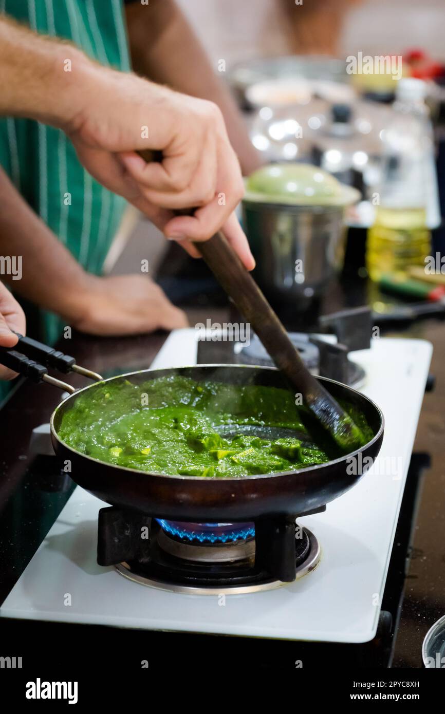 Traditional way of preparing indian food palak paneer (spinach with cheese) using gas pan. Picture of traditional India cuisine made of fresh ingredie Stock Photo