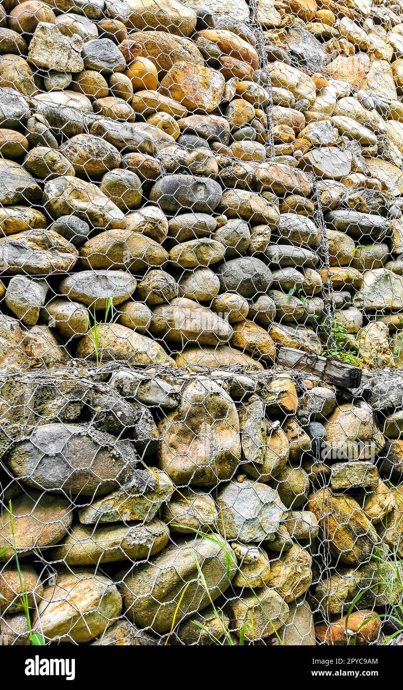 Stones rocks pinned behind a net in Mexico Stock Photo - Alamy
