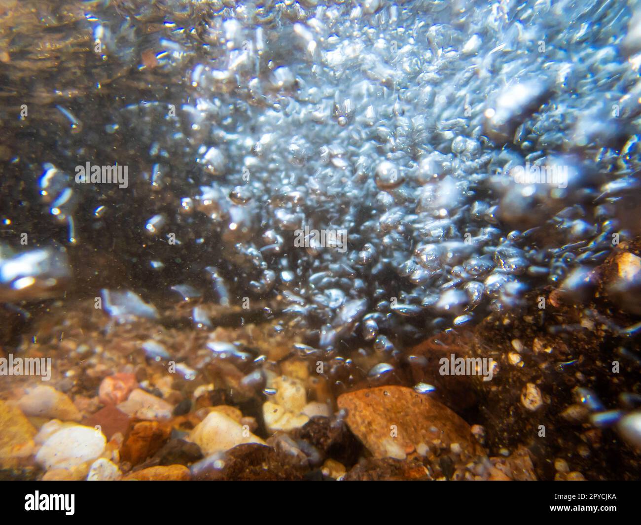Underwater abstract image of a bubbles in stream with colorful stones Stock Photo
