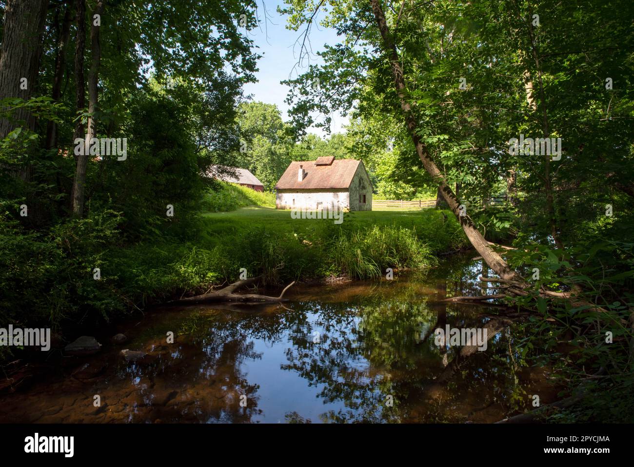 Idyllic colonial whitewashed stone cottage by a stream Stock Photo