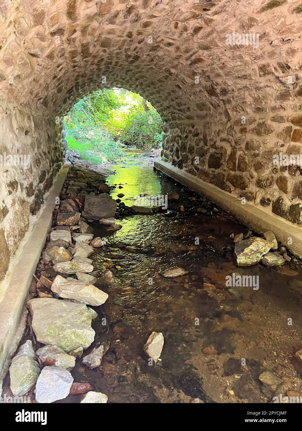 Idyllic stream flows through a colonial stone arch bridge Stock Photo