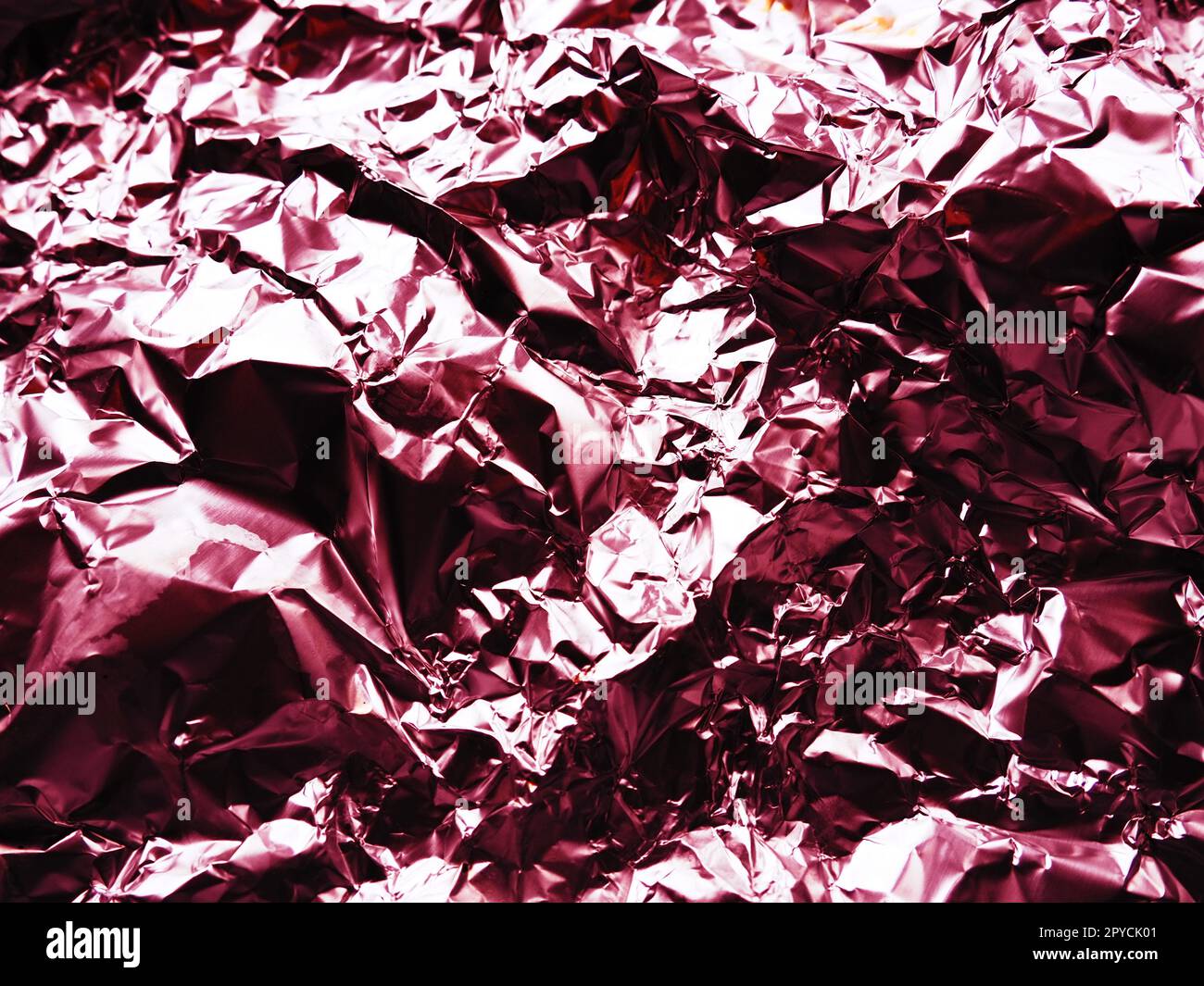 foil close-up. Aluminum silver crumpled foil. Abstract metallic background. Foil for baking food. Background with a red or burgundy tint Stock Photo