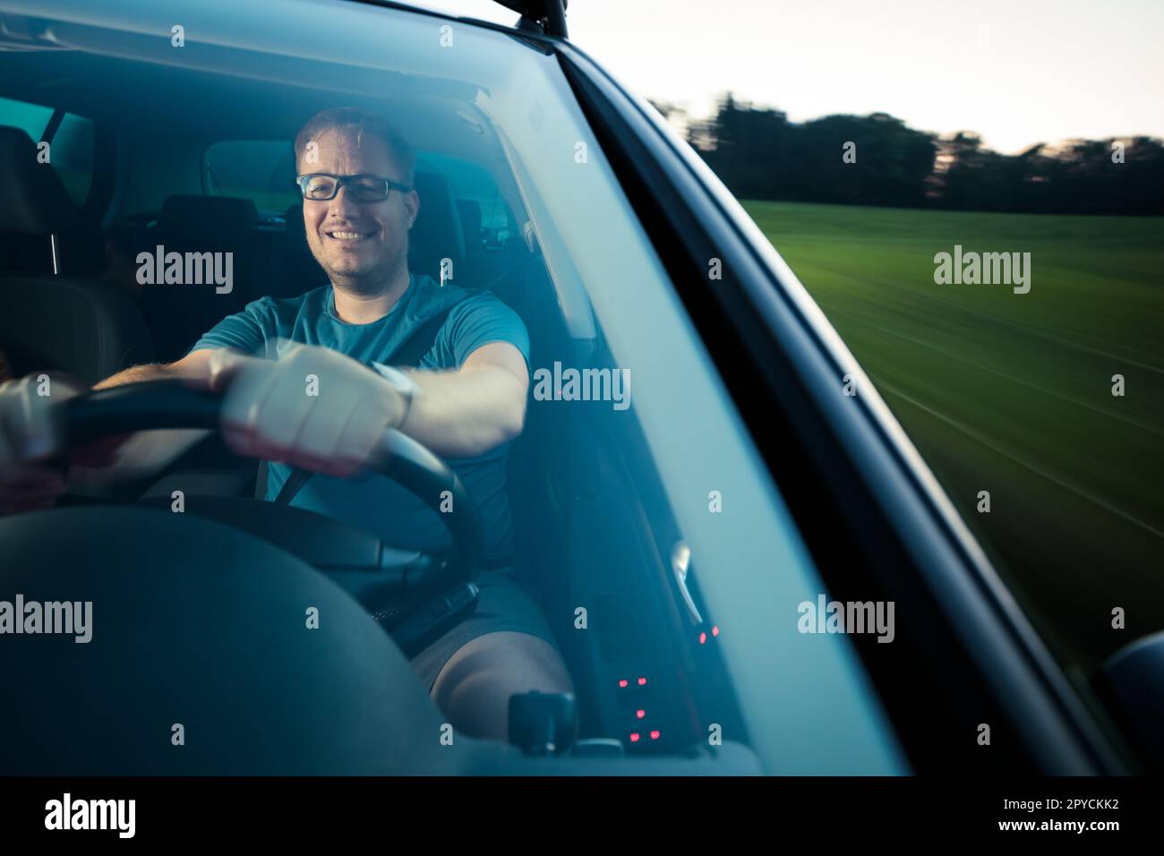 Handsome young driver driving his car fast yet safely on the road (motion blurred image) Stock Photo