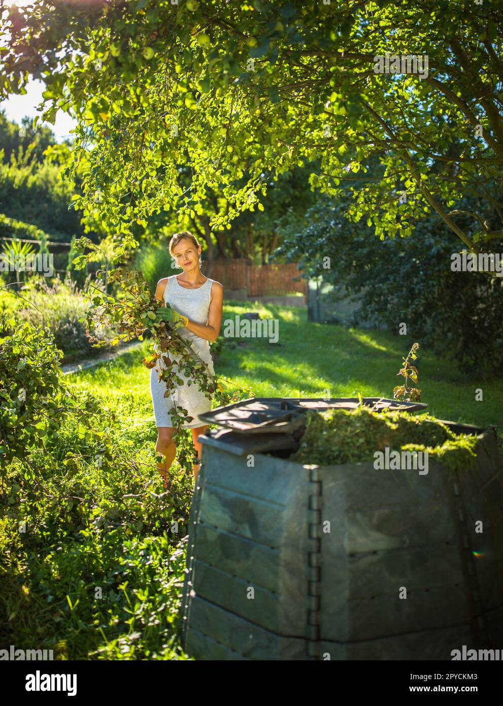 Pretty, young woman gardening in her garden, cutting branches