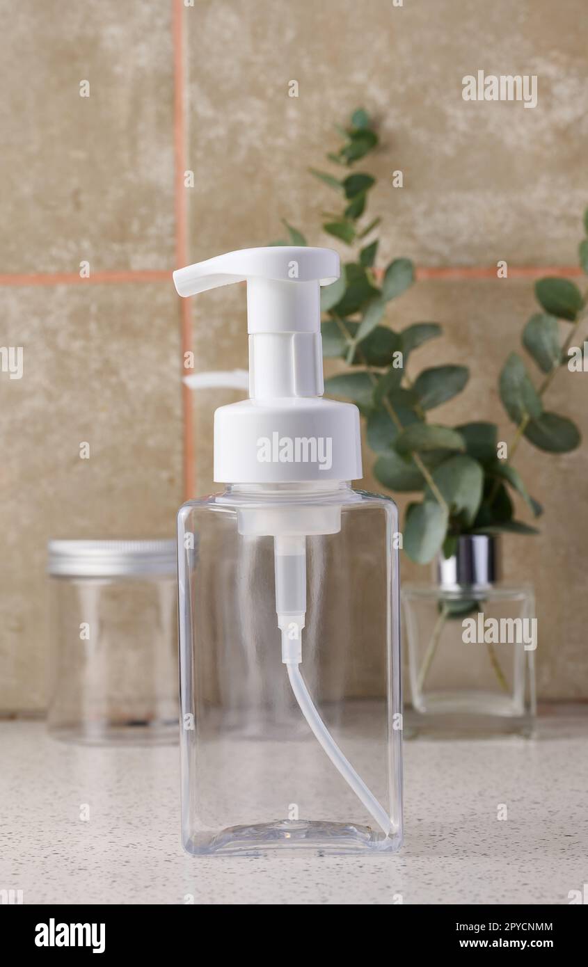 Transparent plastic container with a dispenser on the table. Bottle for liquid soap, shampoo Stock Photo
