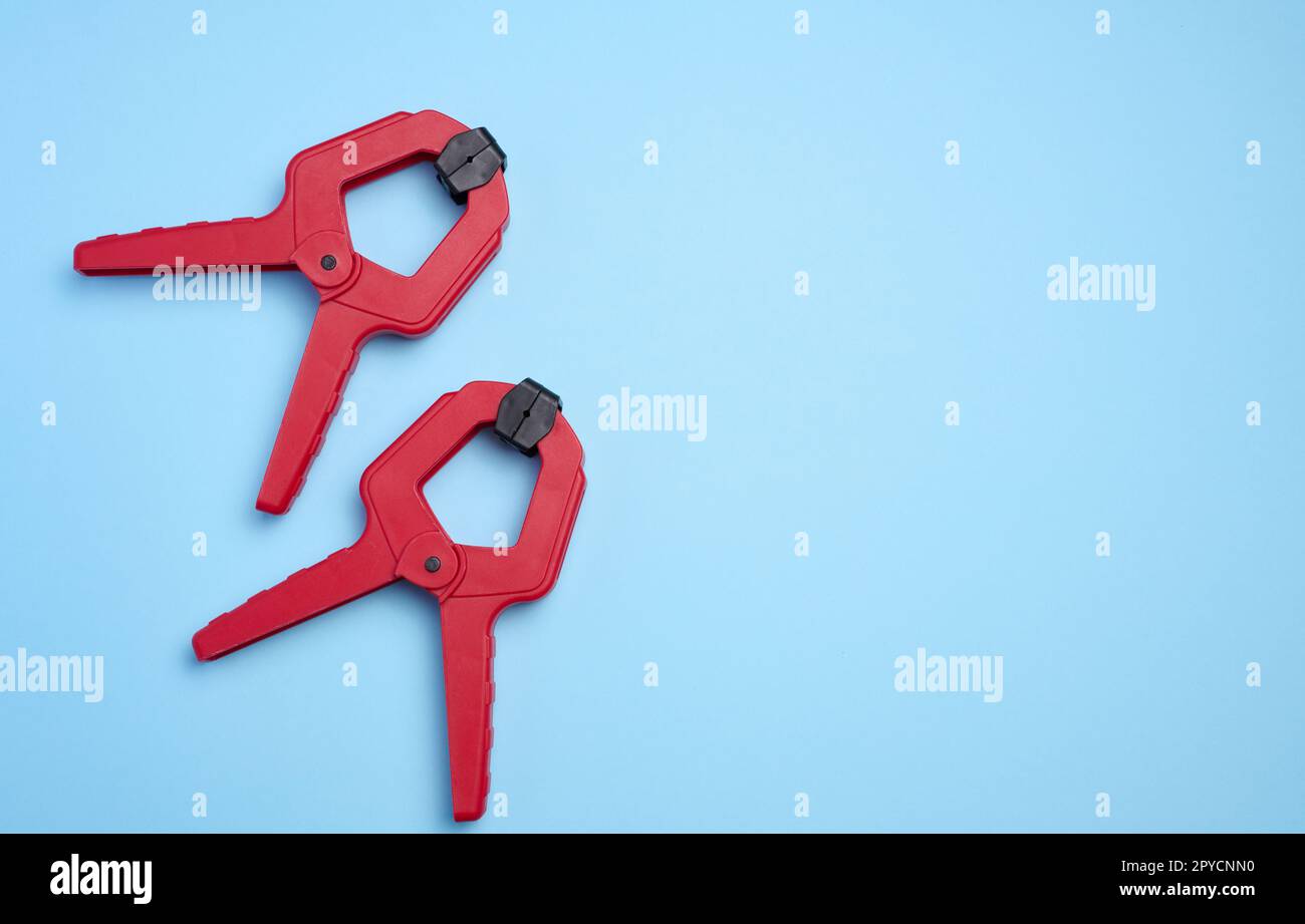 Large  red plastic clamp on a blue background, copy space Stock Photo