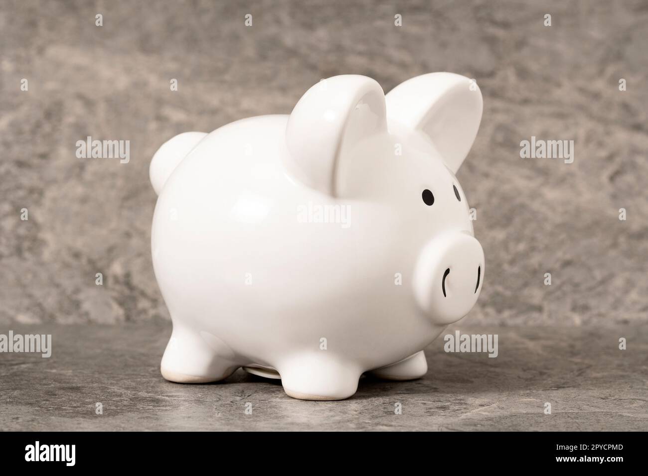 White piggy bank on a grey stone background Stock Photo - Alamy